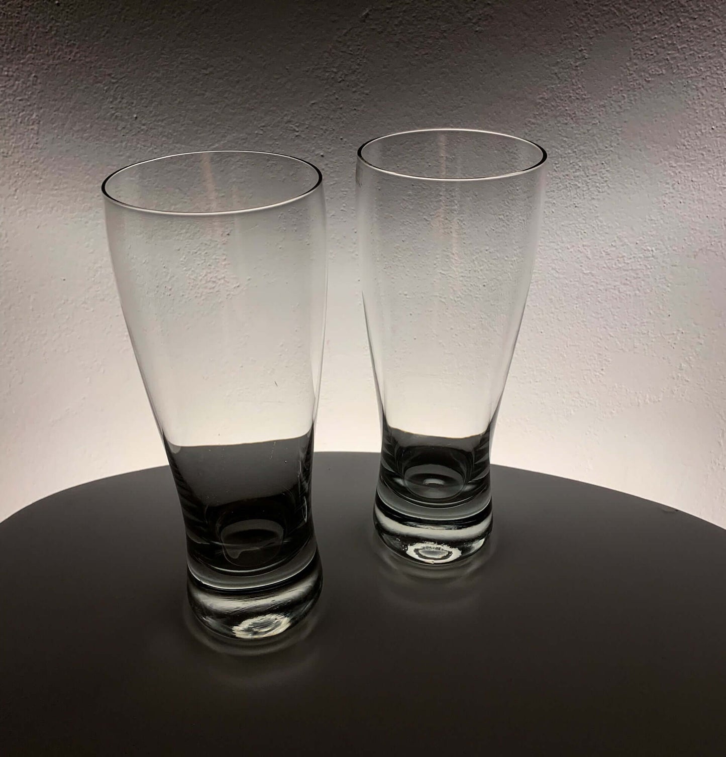 Vintage Saara Hopea beer glasses on a table with soft backlighting, showcasing their elegant design.